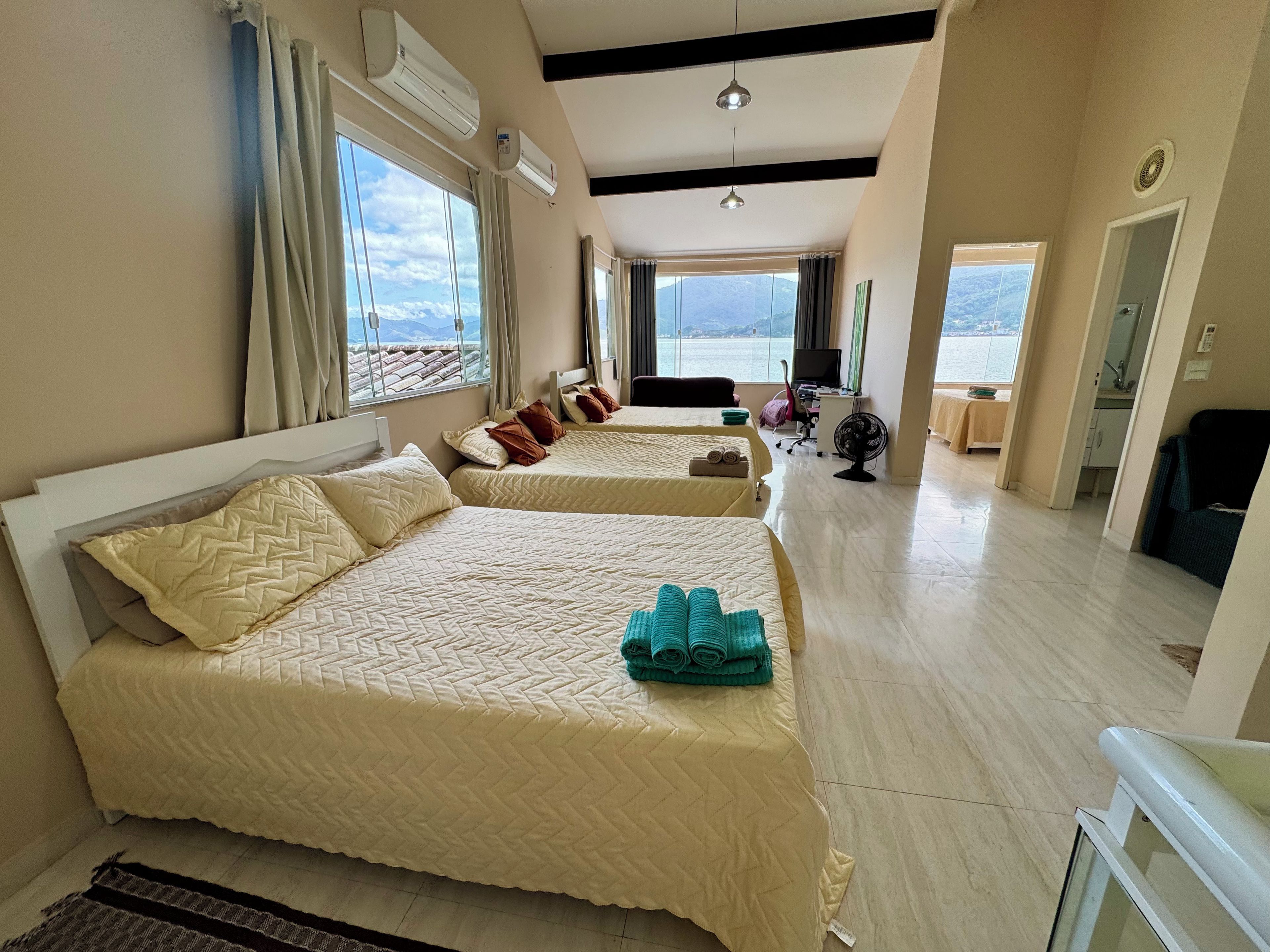 Une chambre d’hôtel avec deux lits, un bureau, une chaise et une vue sur la mer.