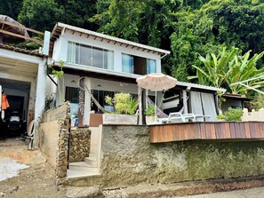 Une maison à deux étages avec un balcon, un hamac et une plante en pot.