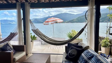 Un sillón hamaca y un sofá mirando a un lago con montañas al fondo.
