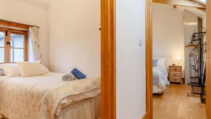 Un dormitorio con cama, ventana, puerta de madera y un pasillo que lleva a otra habitación.