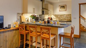 Una cocina moderna con una isla central, sillas de madera y una mesa de comedor.