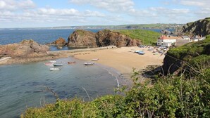 A coastal beach with boats, a sandy shore, rocky outcrops, and buildings in the background. - 4 Bed in Kingsbridge (oc-90027) (South Huish)