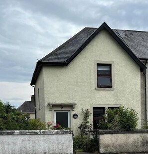 Ein zweistöckiges Haus mit Satteldach, einer Haustür und einem kleinen Fenster.