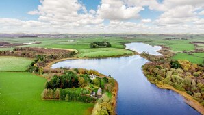 A river meandering through a rural landscape with fields and a small house by the water. - 4 Bed in Ayr- (oc-90038) (Ayr)