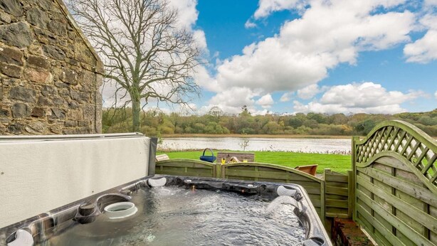 A hot tub with a view of a lake and a stone wall. - 4 Bed in Ayr- (oc-90038) (Ayr)