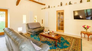Un salon comprenant un canapé, une table basse, une cheminée, un lustre et un téléviseur fixé au mur.