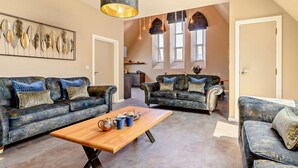 Un salon spacieux avec deux canapés, une table basse en bois et un coin repas à l’arrière-plan.