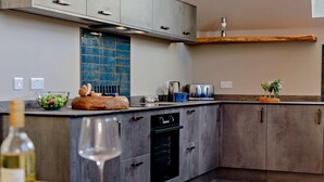 Une cuisine moderne avec des meubles gris, un pare-feu bleu et un plan de travail en bois.