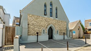 Une église avec une façade en pierre, un toit triangulaire et un parking.