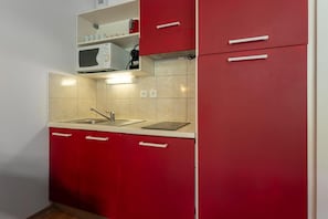 A compact kitchen with a sink, a microwave, and red cabinets. - 200m from ski slopes, swimming pool, balcony, tv, ski locker, 24m², Les Orres (Les Orres)