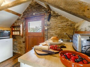 Eine gemütliche Küche mit einer Steinwand, Holzbalken, einer Mikrowelle, einem Toaster und einer Schüssel mit Beeren.