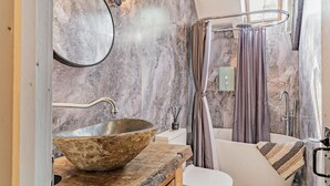 Ein Badezimmer mit einem Becken aus Stein, einer Badewanne und einer Duschvorhang.