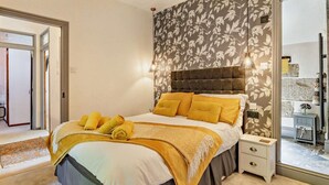 Ein Schlafzimmer mit einem Bett, Nachttischen, einer Chandelier und einem Spiegel.