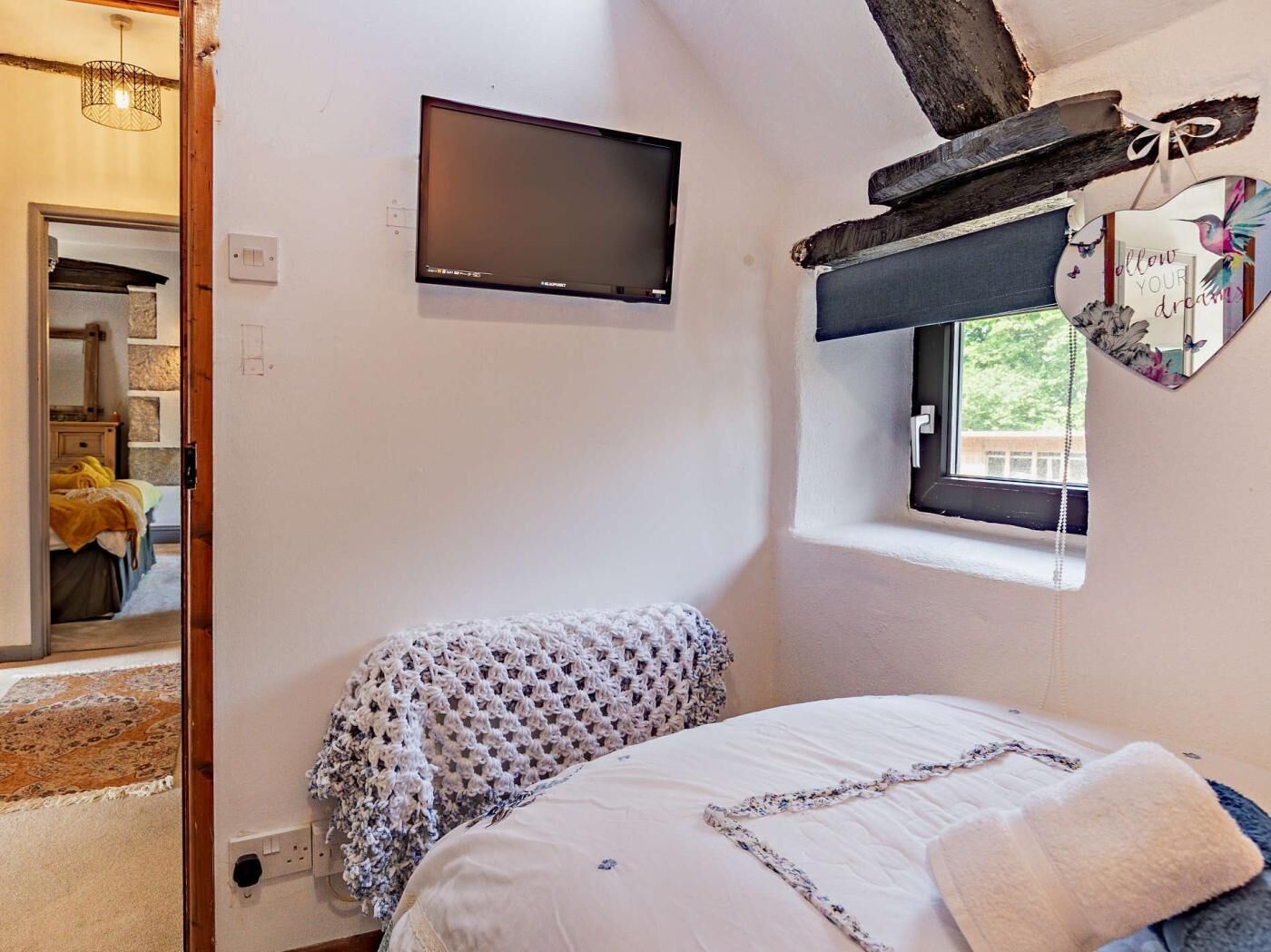 A bedroom with a bed, a television, a window with a view, and a door leading to another room.