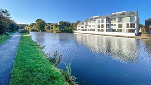 Ein Kanal mit einem Weg an einer Seite und einem modernen Gebäude mit mehreren Etagen und Balkonen an der anderen.