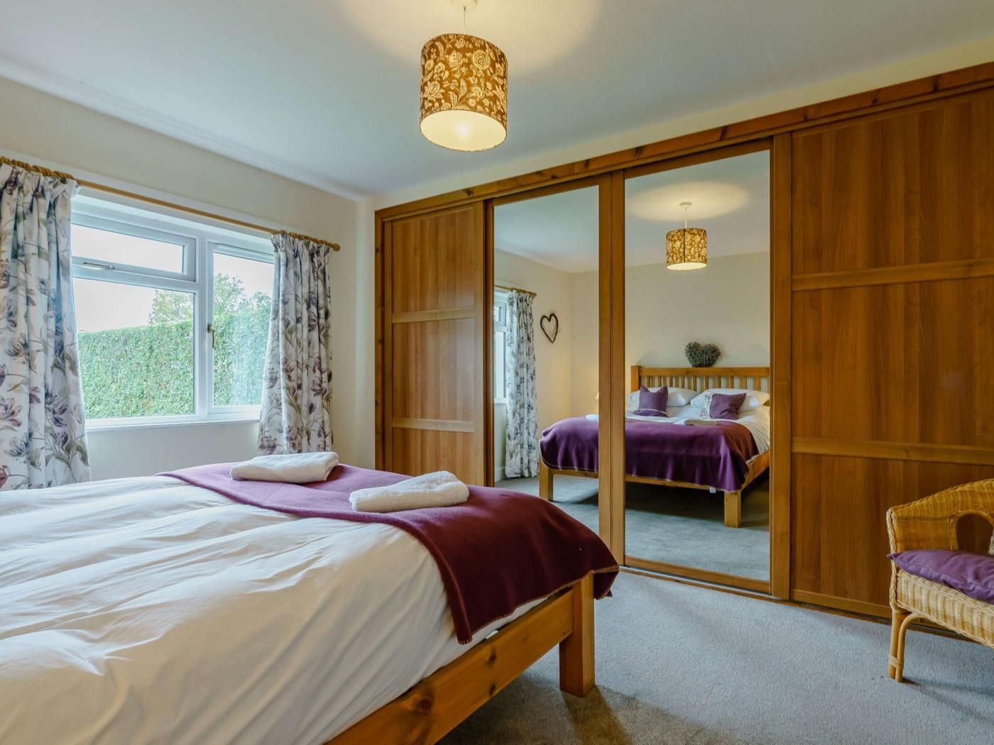 A bedroom with a bed, a wardrobe, a mirror, and a window.
