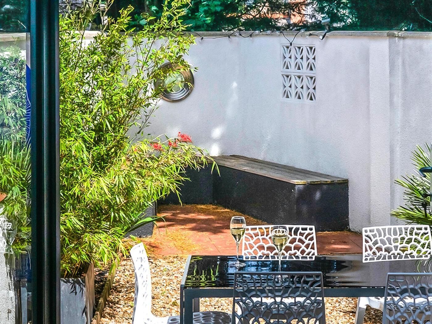 A patio area with a seating arrangement, a small table with a glass, and a decorative fence.