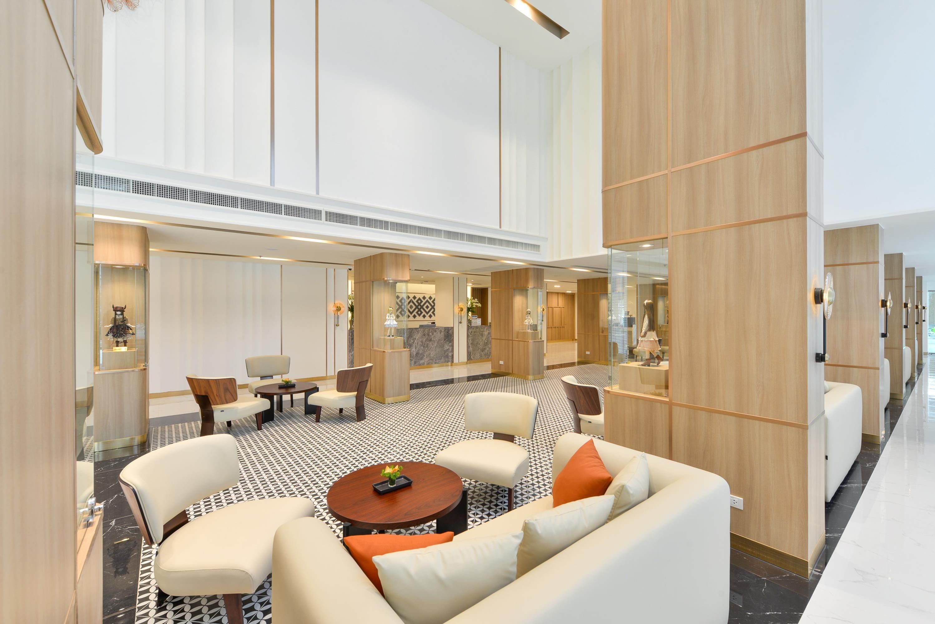 A modern hotel lobby with a seating area, a reception desk, and a patterned floor.