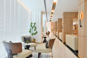Un moderno vestíbulo de hotel con zonas de estar, un mostrador de recepción y vistas a las habitaciones.