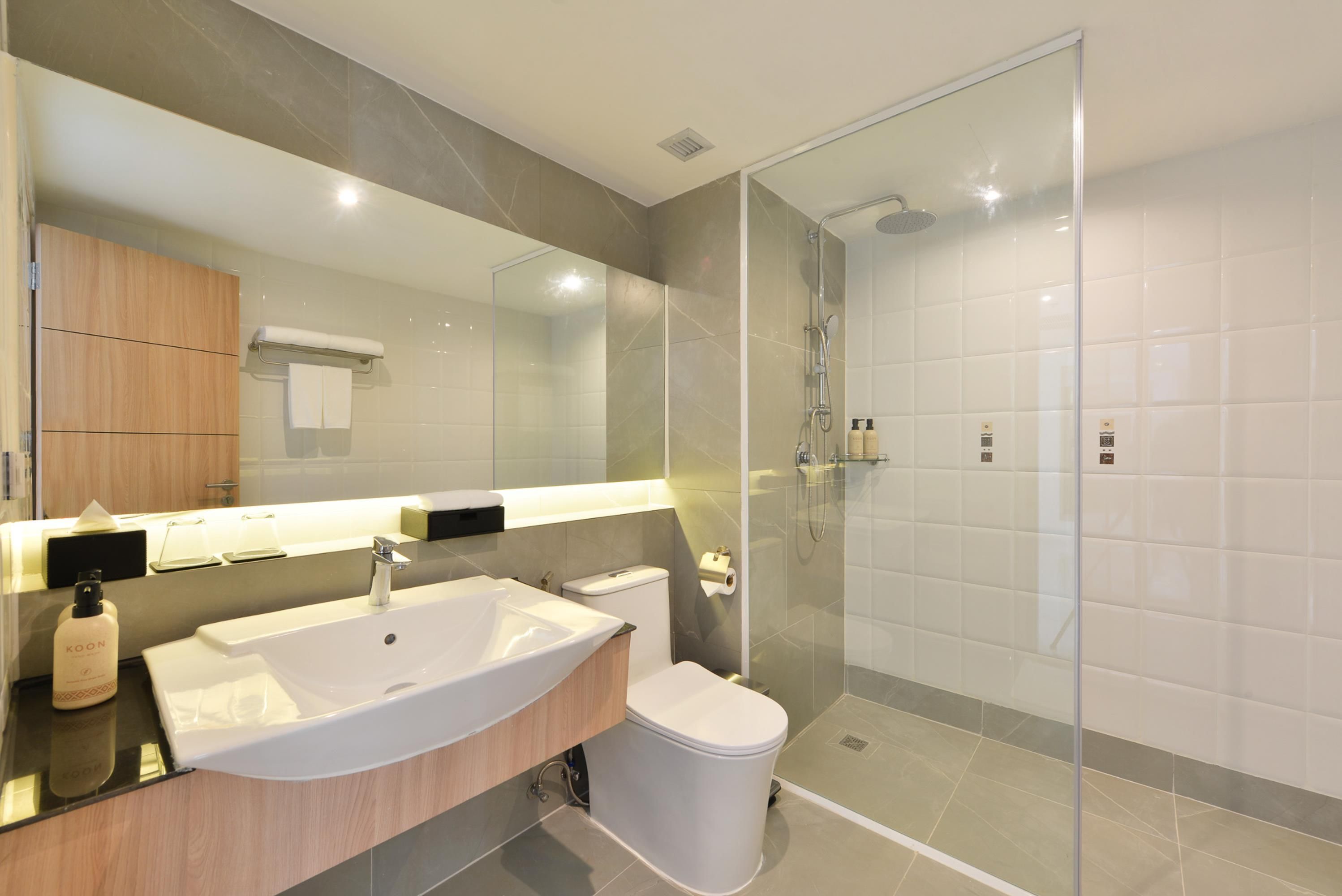 Un baño moderno con ducha envuelta en vidrio, lavamanos blanco y un inodoro.
