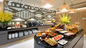 Montaje de bufé con diferentes opciones de comida, una estación de café y plantas decorativas.