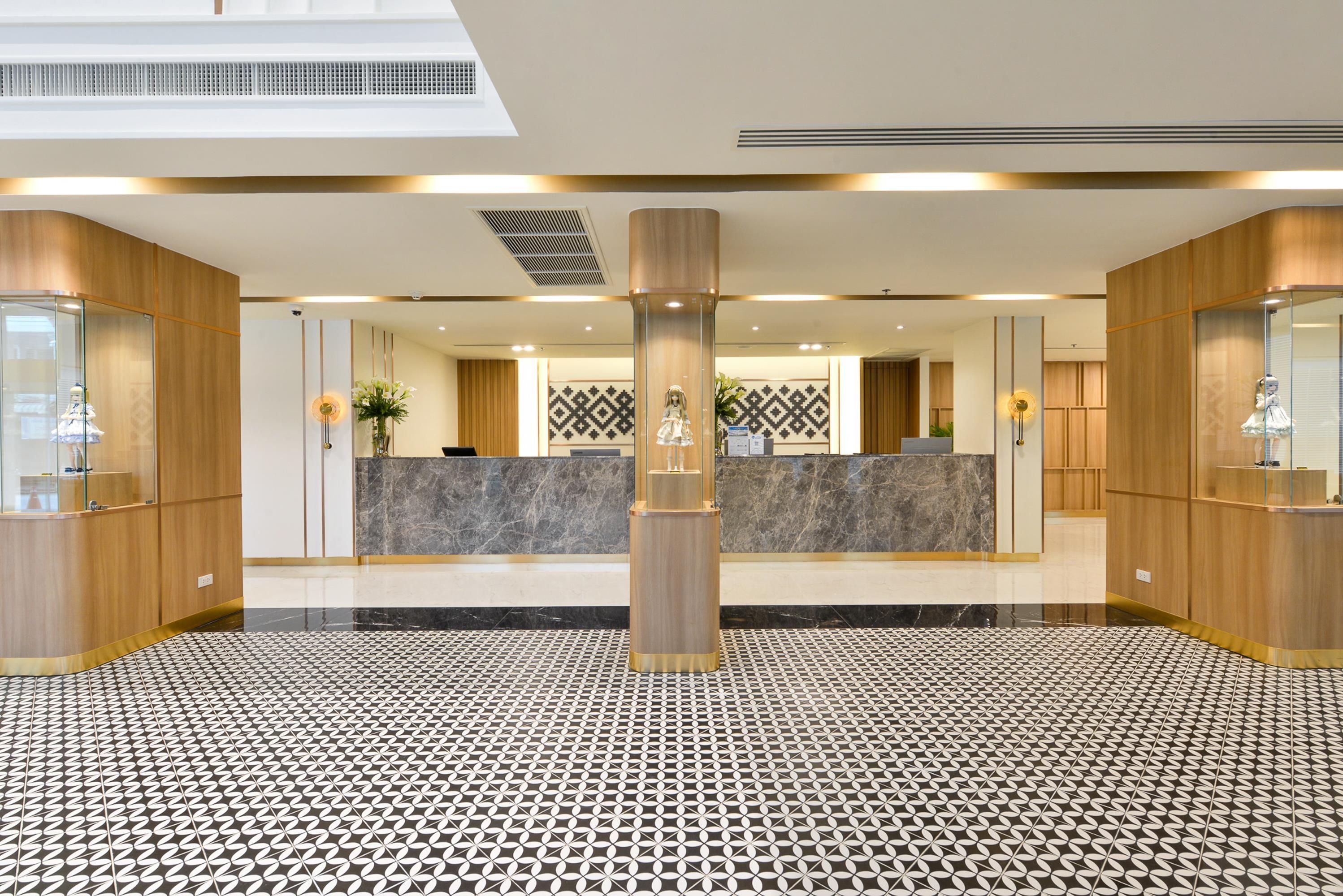 Un vestíbulo de hotel con una recepción, piso estampado y paneles de madera.