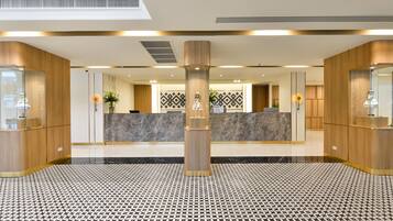 Un vestíbulo de hotel con una recepción, piso estampado y paneles de madera.