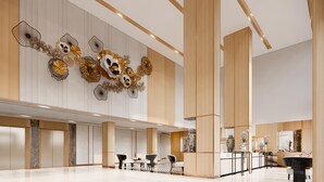 Un vestíbulo espacioso con diseño moderno, que cuenta con una zona de estar central, una recepción y arte decorativo en las paredes.