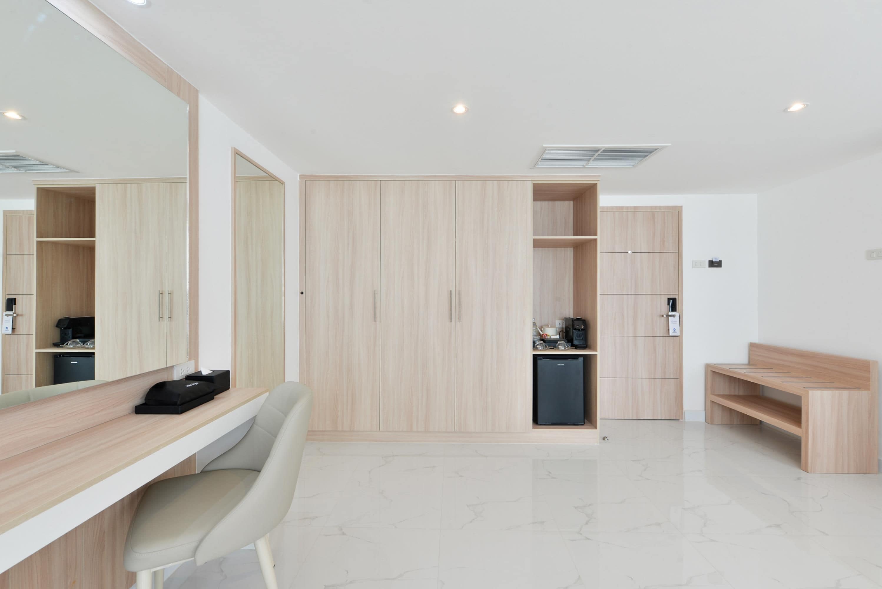 A modern, well-lit room with a desk, chair, and a large wardrobe with multiple compartments.