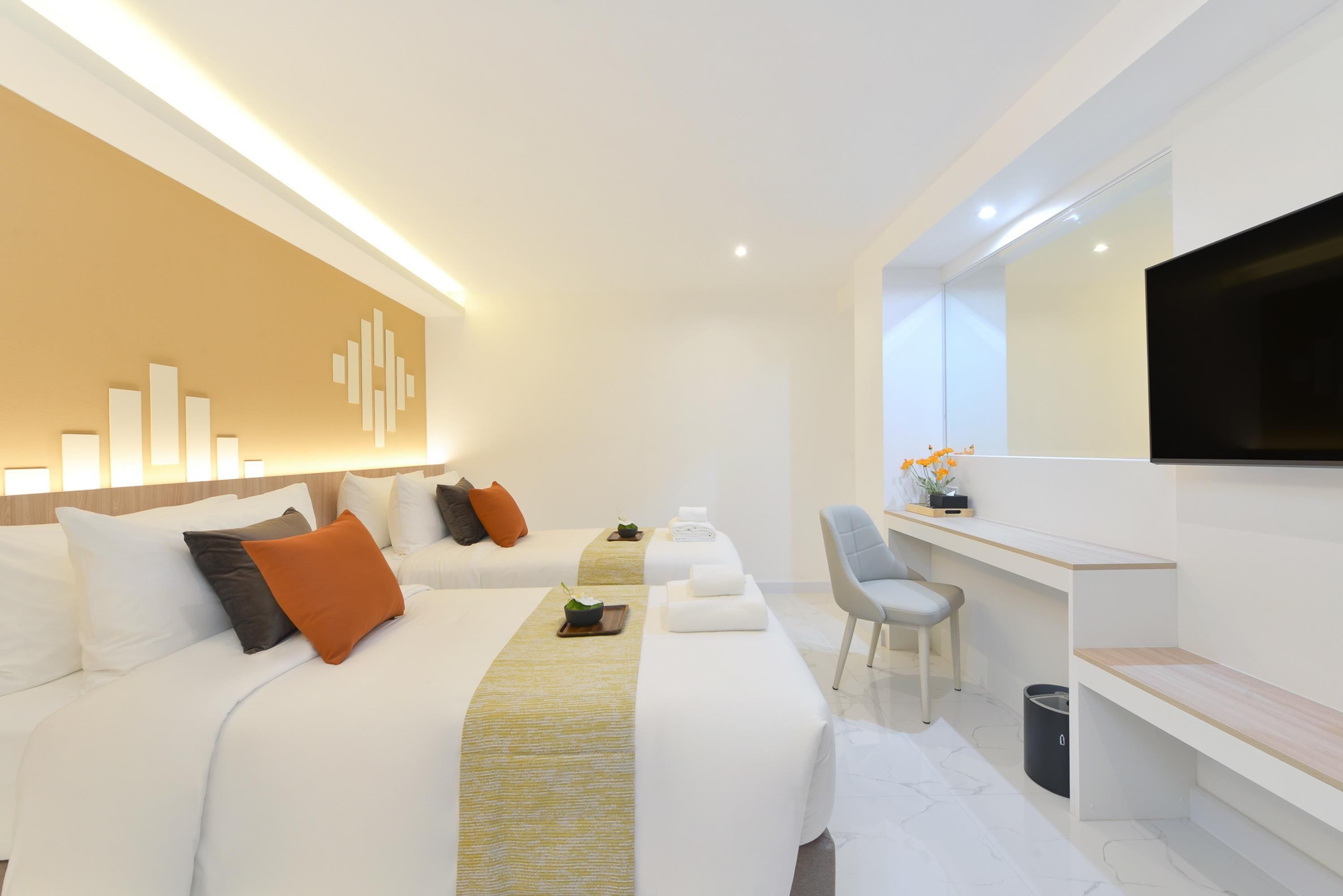 A modern hotel room with a large bed, a desk, a chair, and a flat-screen TV.
