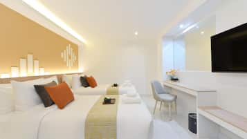 A modern hotel room with a large bed, a desk, a chair, and a flat-screen TV.