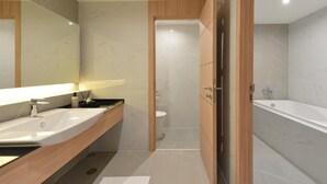 Un baño moderno con un espejo grande, un lavamanos y una bañera.