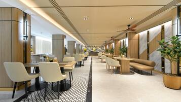 A modern hotel lobby with a central walkway, seating areas, and a staircase.