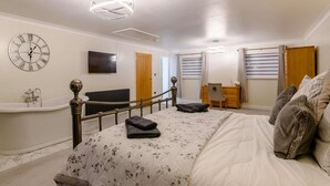 A bedroom with a bed, a vanity, a radiator, a television, a desk, and a staircase. - 4 Bed in Norwich (oc-90094) (Stratton Strawless)