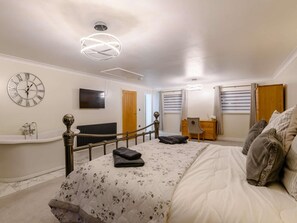A bedroom with a bed, a vanity, a radiator, a television, a desk, and a staircase. - 4 Bed in Norwich (oc-90094) (Stratton Strawless)
