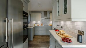 A modern kitchen with stainless steel appliances, grey cabinetry, and a marble backsplash. - 5 Bed in Aberdovey (oc-90222) (Aberdovey)