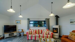 A living room with a sofa, a coffee table, a fireplace, a television, and pendant lights. - 5 Bed in Aberdovey (oc-90222) (Aberdovey)