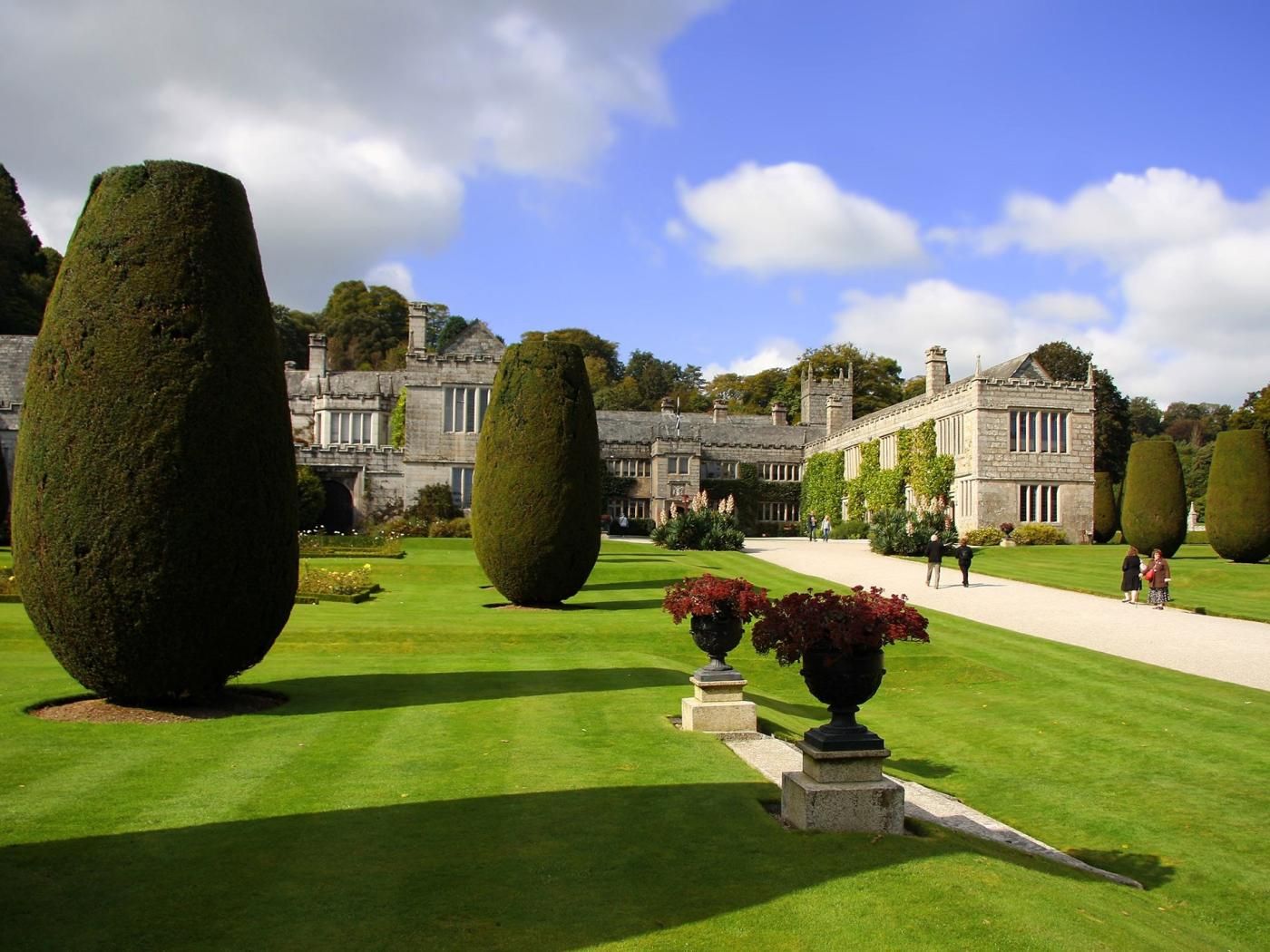 A formal garden with neatly trimmed hedges and a historic building in the background.