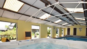 Una piscina interna con idromassaggio, ampie finestre e un cartello che indica la profondità.