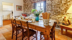 Un'area pranzo rustica con parete in pietra, tavolo e sedie in legno.