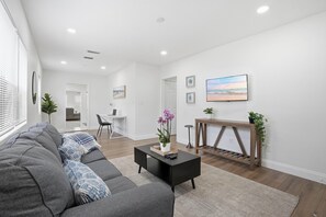 A modern living room with a gray sofa, a black coffee table, and a wooden console table with a plant. - Spacious and comfortable house in Avondale. Ideal for longer stays. Pet friendly (Jacksonville)