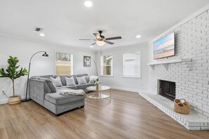 A modern living room with a grey sectional sofa, a round coffee table, a fireplace, and a ceiling fan. - Spacious and comfortable house in Avondale. Ideal for longer stays. Pet friendly (Jacksonville)