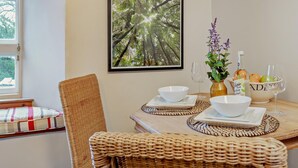 A dining area with a table set for two, a framed forest photograph on the wall, and a window with curtains. - 1 Bed in Kirkby Stephen (oc-89457) (Crosby Garrett)