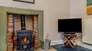 A room with a fireplace, a television, and a rustic wooden table. - 1 Bed in Kirkby Stephen (oc-89457) (Crosby Garrett)