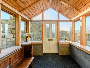 Ein gemütliches Zimmer mit Steinwand, einer hölzernen Bank und einer Tür mit satinierten Glasscheiben.