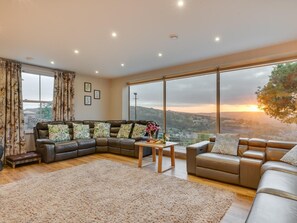 Ein geräumiges Wohnzimmer mit großem Fenster, einer Ledersofa, einem zusätzlichen Sofa, einem Couchtisch und einem Teppich.