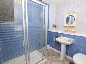 Ein Badezimmer mit Duschkabine aus Glas, einem weißen Waschbecken und einer Toilette.