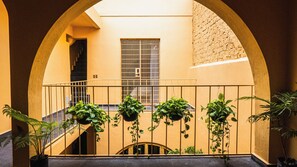 A courtyard with a staircase, a barred window, and potted plants. - Casa Juan Álvarez  (Guadalajara)