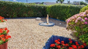 Ein Garten mit Brunnen, Kiesweg und unterschiedlichen Pflanzen.