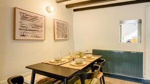 A dining area with a table set for four, chairs, and two framed artworks on the wall. - 2 Bed in Ilfracombe (oc-89570) (Combe Martin)